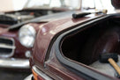 Sponge strip fitted along a maroon classic car's bonnet edge, hammer nearby