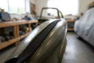 Black felt strip fitted along a classic car's wing edge in a workshop setting