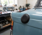 Round black fuel send unit cover fitted to a blue car's rear wing