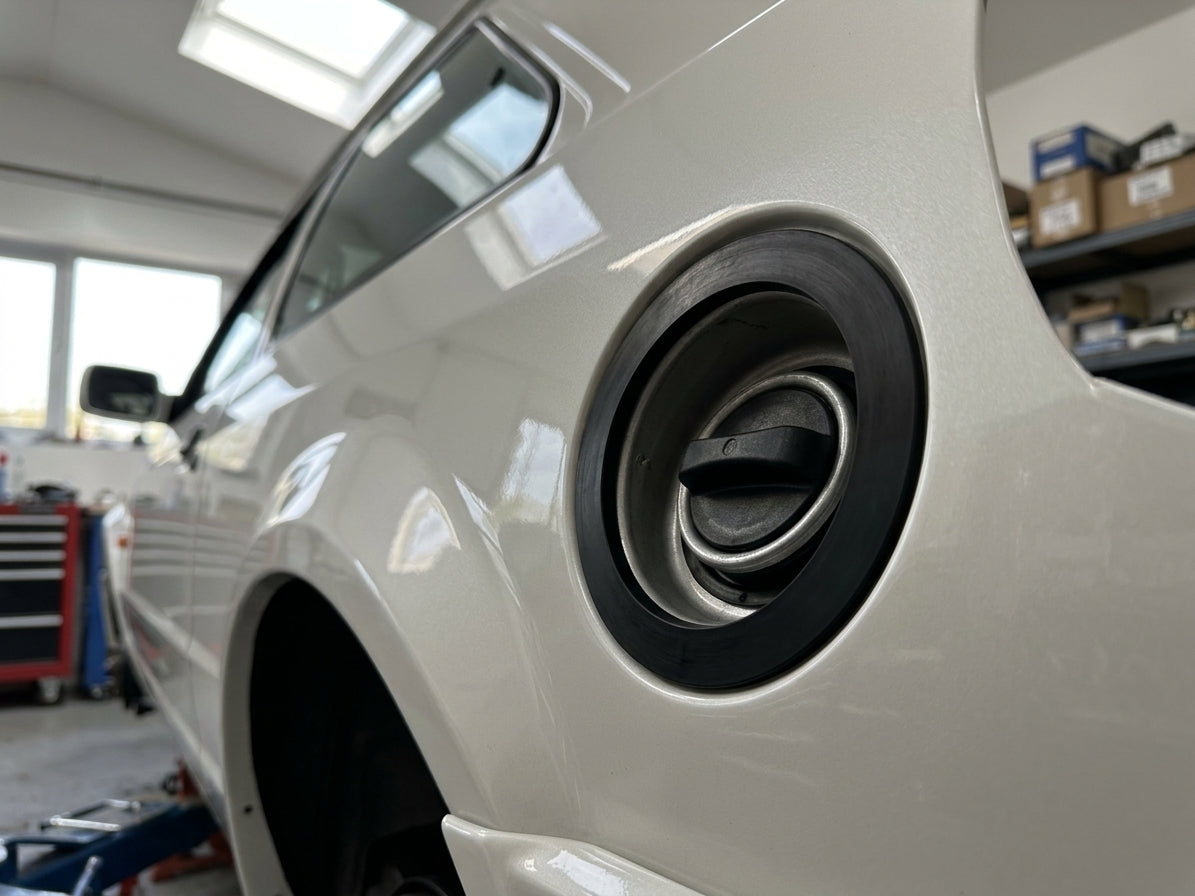 Black fuel cap seal fitted around a cream Escort's fuel filler flap