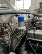 Fuel pump with blue cap mounted under the bonnet of a classic car near the windscreen