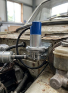 Fuel pump with blue cap fitted in the engine bay of a weathered classic car
