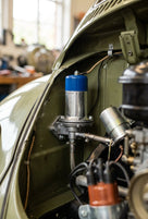 Fuel pump with blue cap fitted in the engine bay of a green classic car, braided fuel line attached
