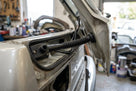 Black tailgate grommet fitted between a white car's open tailgate and body