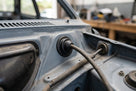 Black cable grommet with speedo cable fitted through a blue car's bulkhead