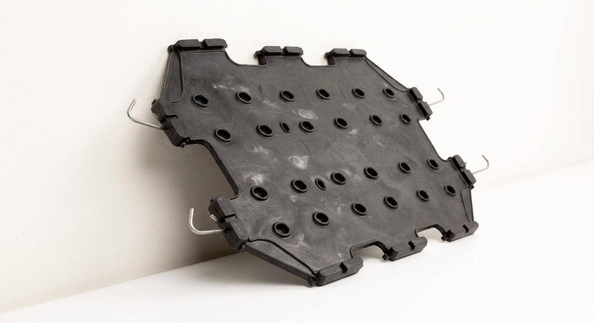 Black perforated seat diaphragm panel with fitting hooks, studio shot