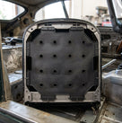 Black perforated seat diaphragm fitted in a seat back frame inside a car