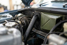 Pipe fitted in the engine bay of a blue classic car, near the heater box