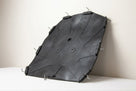 Black moulded seat diaphragm with metal hooks, leaning against a studio wall