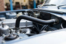 Black heater hose fitted between the rocker cover and bulkhead in an engine bay
