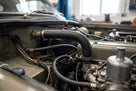 Black heater hose fitted beside the carburettors in a Triumph engine bay