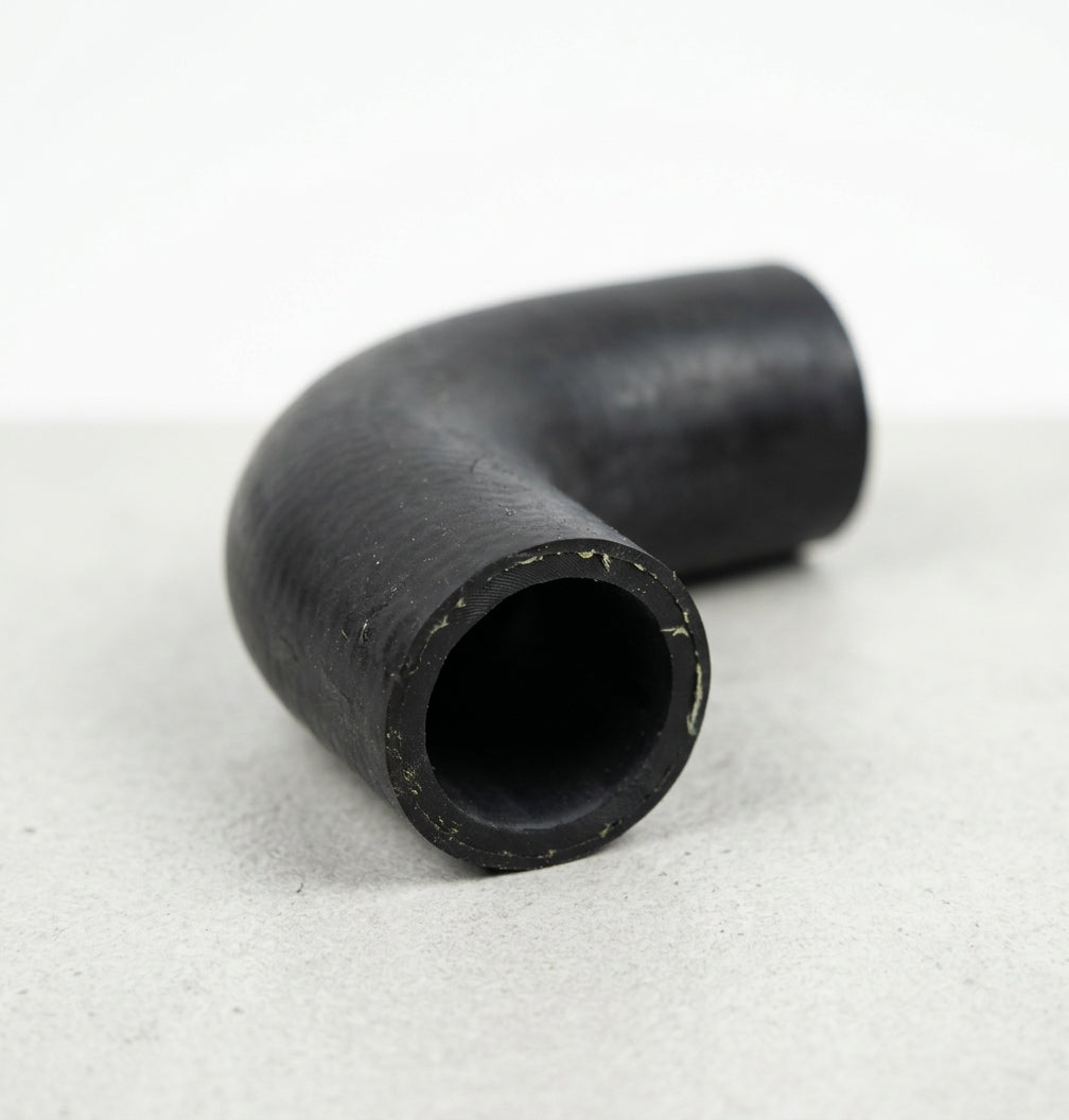 Black rubber elbow hose on grey, tight bend with pale reinforcement threads showing round the open cut bore