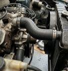 Black rubber hose connecting the radiator to the engine, secured with metal clips