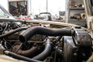 Black top radiator hose fitted between engine and radiator in a cream classic car