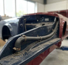 Drainage hose fitted along the bulkhead of a part-stripped Triumph