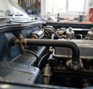 Heater hose fitted from bulkhead to engine on a blue-grey Triumph