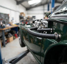 Heater feed hose fitted to the carburettors of a green Triumph's engine
