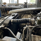Ribbed black rubber radiator hose fitted between radiator and engine in a car bay