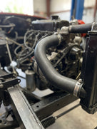 Black radiator hose connecting engine to radiator in a classic car engine bay