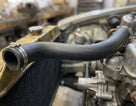Black radiator hose fitted between a brass radiator and engine block