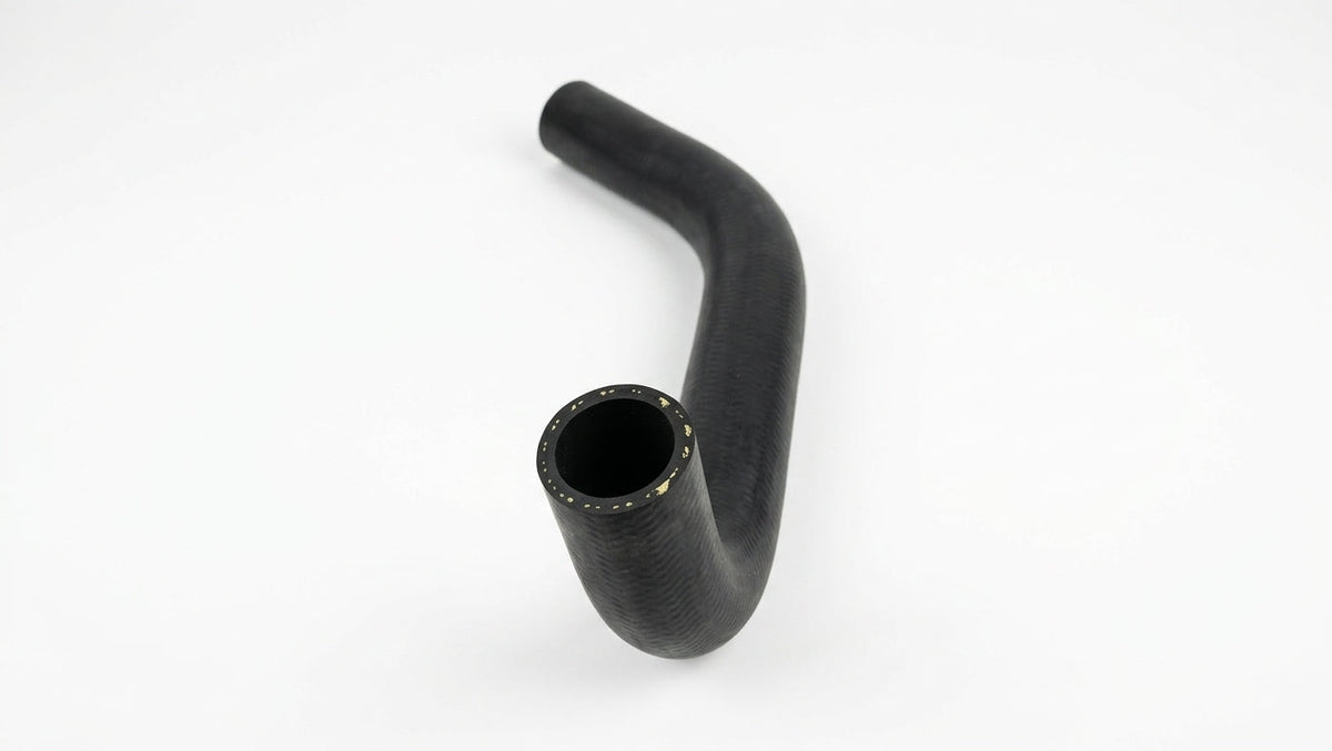 Textured black rubber hose coiled with cut end downward on white studio background
