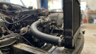 Black radiator hose connecting engine to radiator, fitted in a classic car engine bay