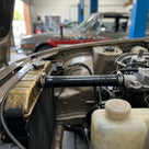 Black hose running from the radiator to the header bottle in an engine bay