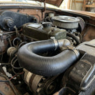 Black radiator hose looped between engine and radiator in a classic car engine bay