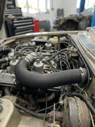 Black corrugated hot air hose fitted across the top of an engine bay