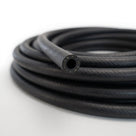 Coiled length of black textured fuel hose showing open bore, studio shot