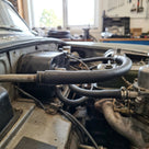 Black braided fuel hose connected in the engine bay of a classic car
