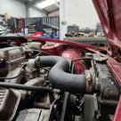 Top radiator hose fitted between carburettors and radiator on a red Triumph TR8