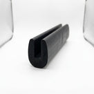 Black neoprene U-channel edge trim standing upright, studio softbox photo of rounded block
