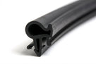 Black rubber seal with barbed leg and hollow bulb, coiled on white background