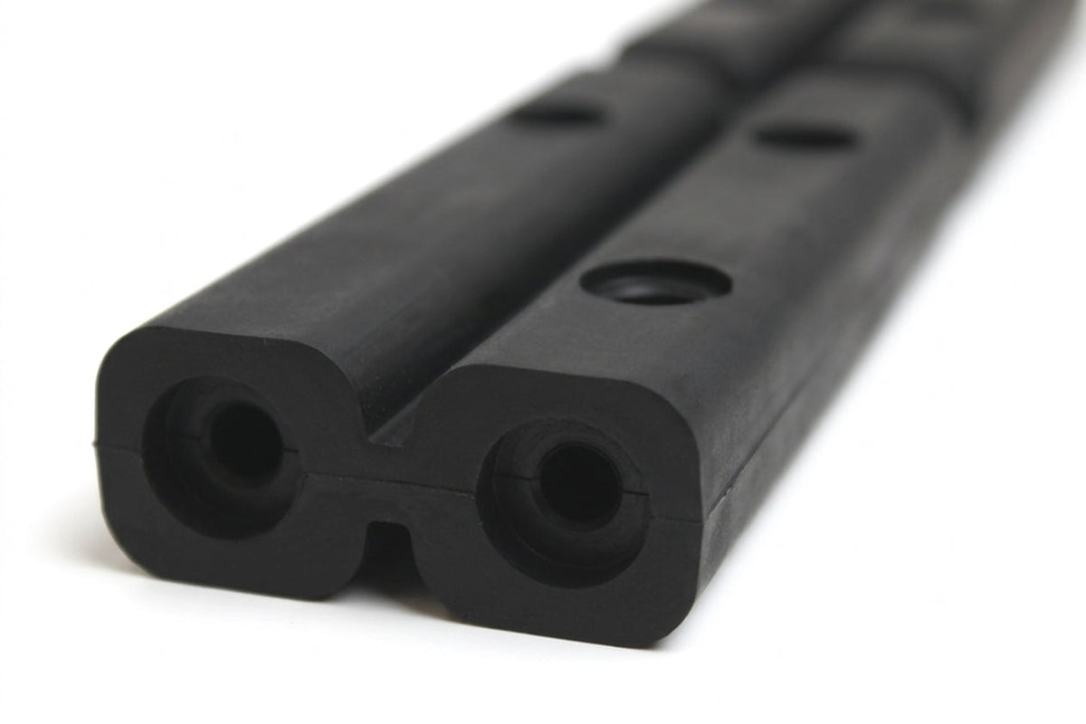 Black rubber tailboard section with twin bolt holes, close-up studio shot