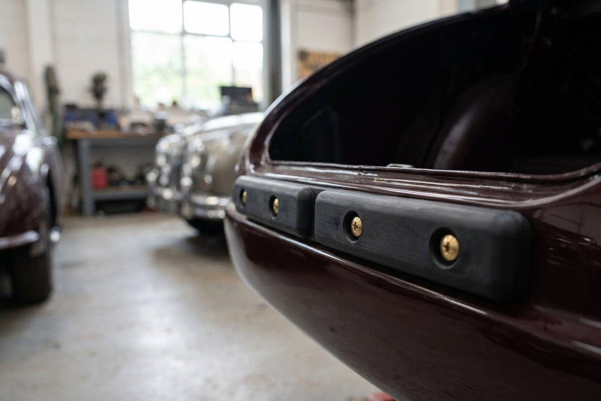 Black tailboard rubber fitted with brass screws on a maroon classic car