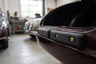 Black tailboard rubber fitted with brass screws on a maroon classic car