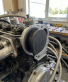 Black rubber cambox end plug fitted to the cylinder head, workshop background