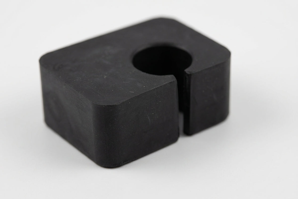 Black rubber seat adjusting block fitted on a car floor pan beside the seat rail