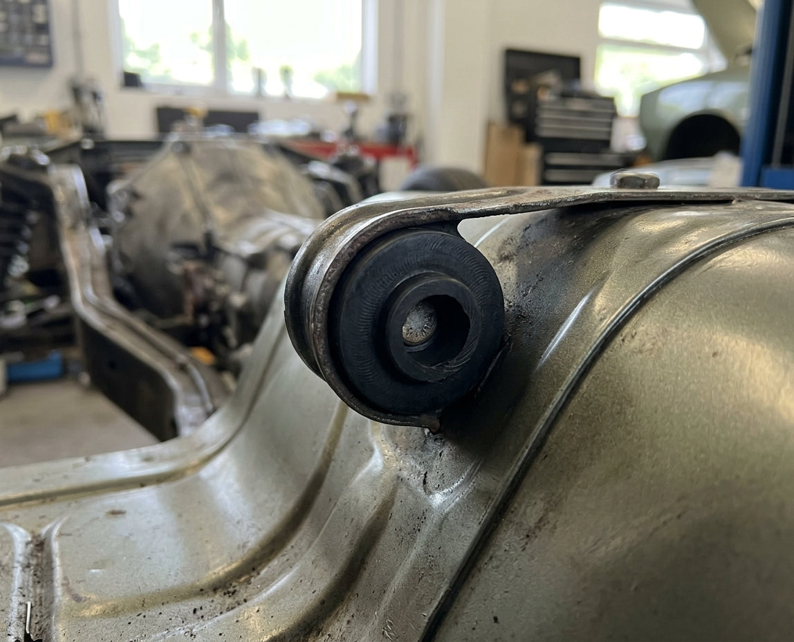 Bush fitted in a body bracket of a light green classic car in a workshop