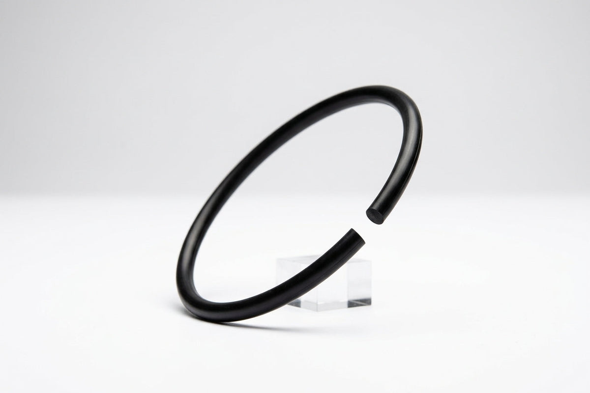 Black rubber cord bent into a ring with a visible join gap, propped on a stand