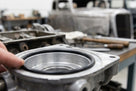 Black O-ring fitted inside an oil pump housing, held by hand for fitting