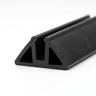 Black triangular rubber trim section with twin internal channels, studio shot