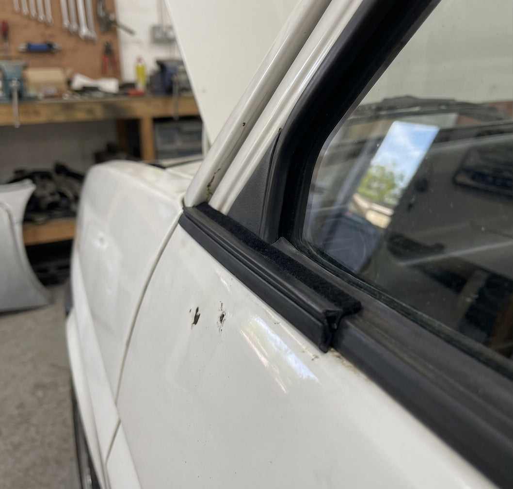 Flocked black outer waist strip fitted along a white car's window edge
