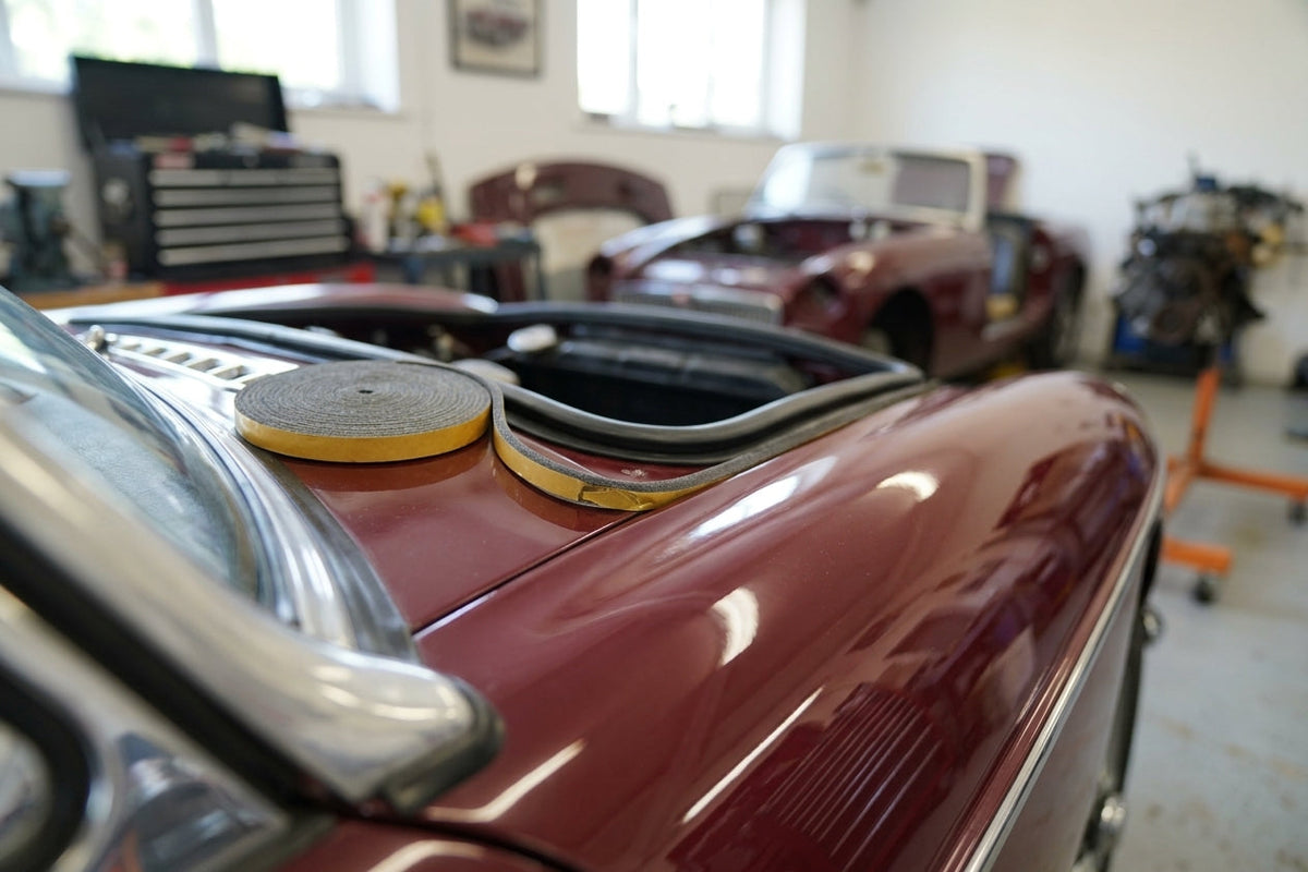 Self-adhesive foam strip fitted along a maroon classic car's bonnet edge
