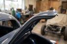 Self-adhesive foam strip fitted along a black classic car's roof edge, in-situ shot