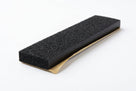 Black foam strip block shown at an angle, gold adhesive backing along one edge