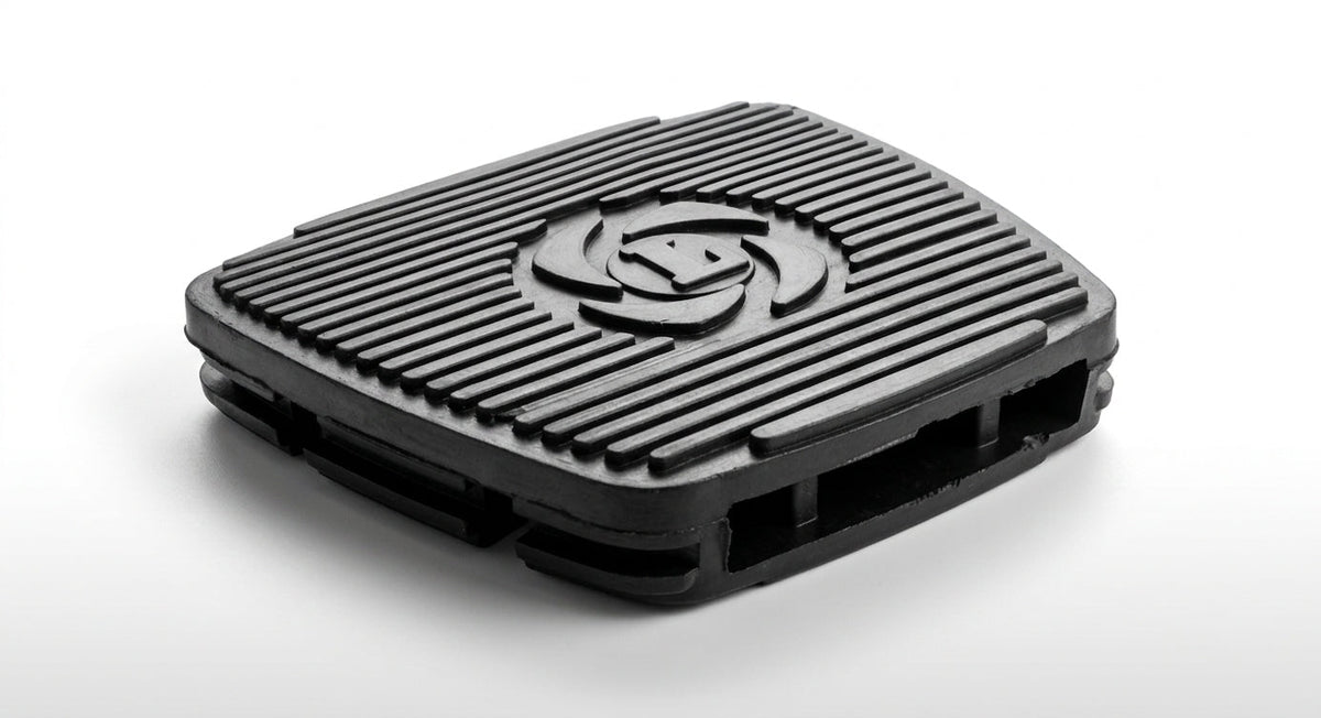 Black ribbed rubber brake pedal pad with embossed logo, studio shot