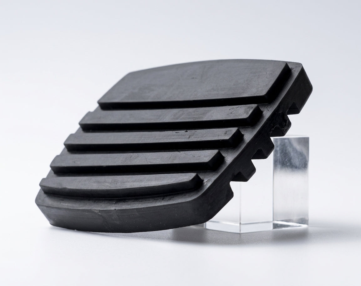 Black ribbed rubber brake pedal pad propped upright on a white background