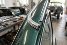 Chrome plastic trim fitted along the roof gutter of a green classic car